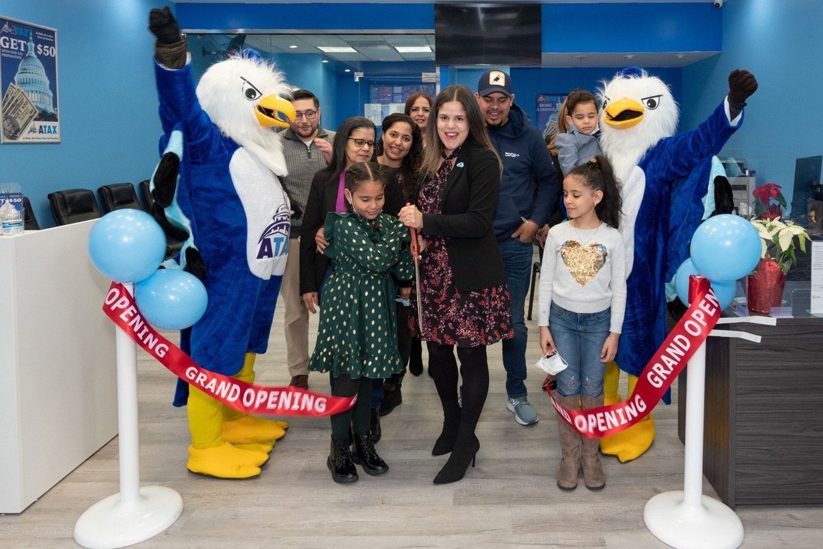 ATAX franchise grand opening — owners and family cutting the grand-opening ribbon at the new bilingual storefront, the start of a multi-generational community business